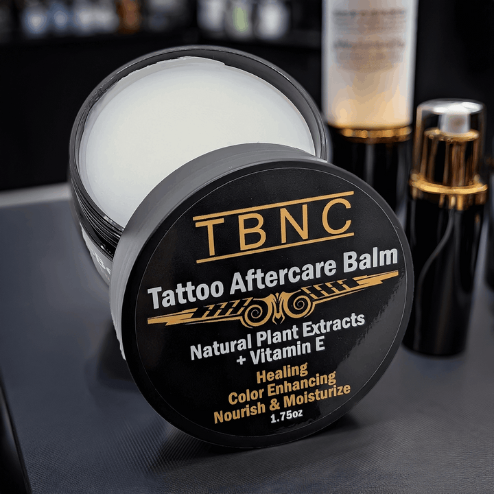 TBNC Tattoo Aftercare Balm container on a dark surface with blurred background
