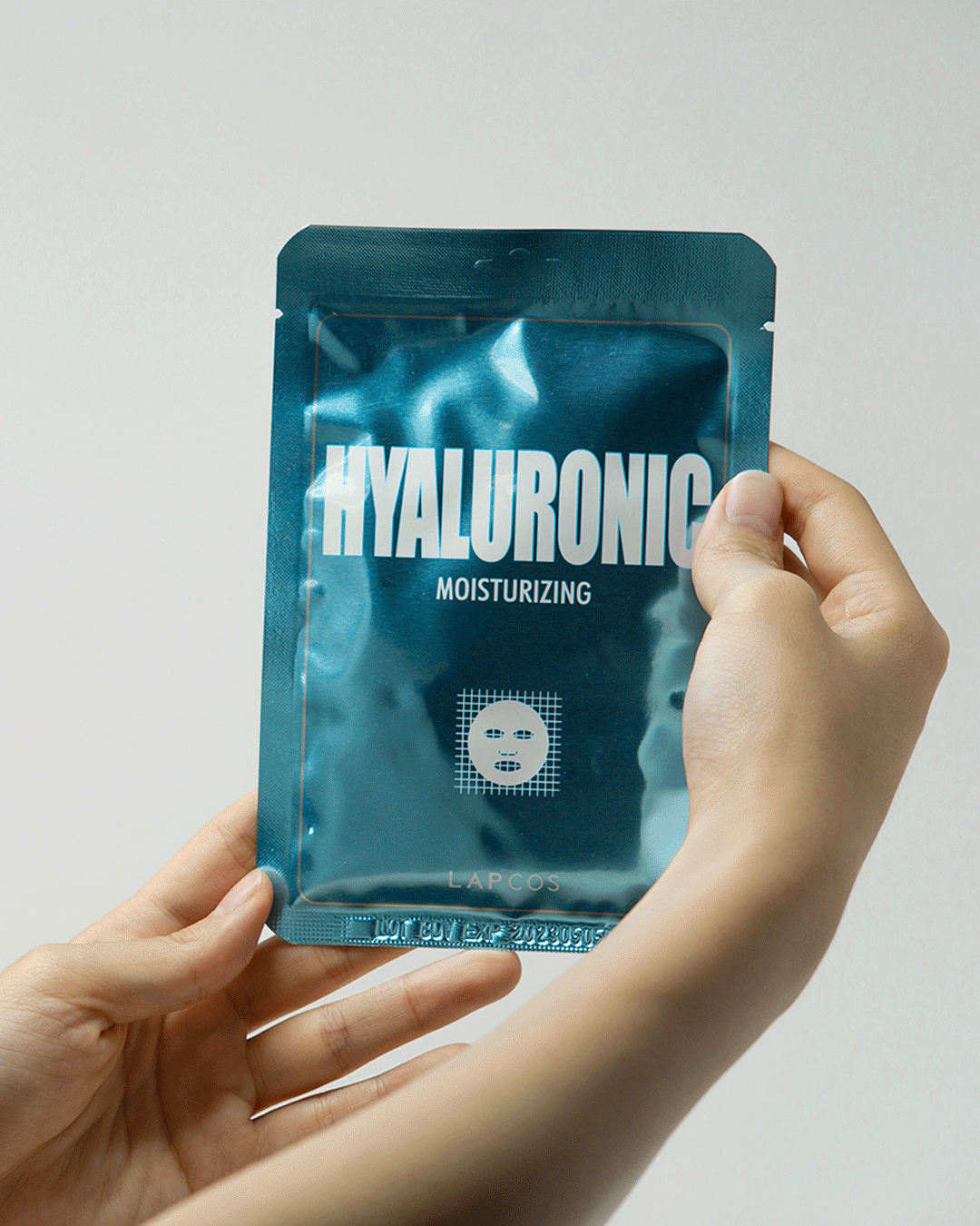 Hyaluronic acid hydrating mask showing person opening sachet of sheet mask