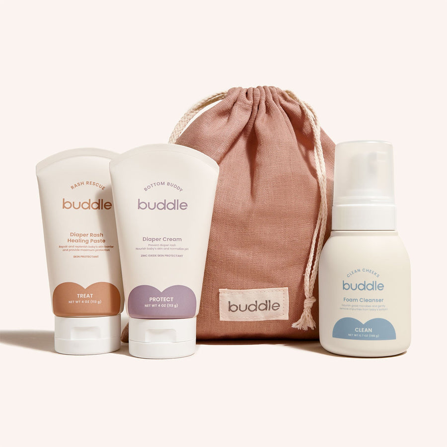 Buddle baby care products including cream, paste, and cleanser with a drawstring bag on a white background.