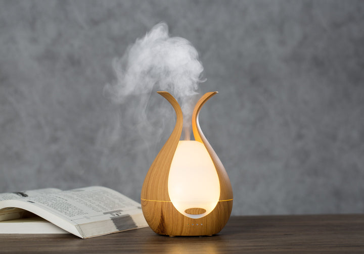 Wooden diffuser emitting steam on a wooden surface with a gray background