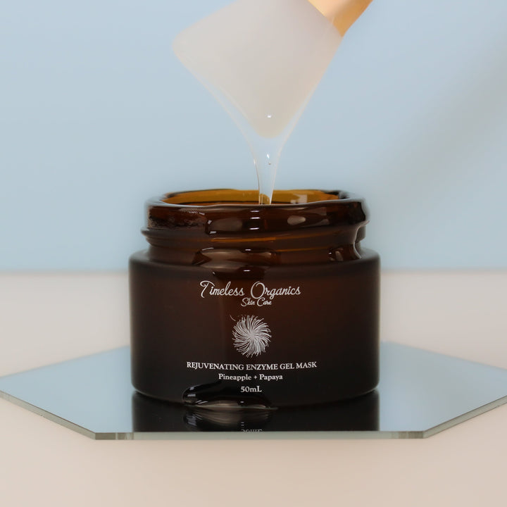 Brown jar of Timeless Organics Rejuvenating Enzyme Gel Mask with a white applicator pouring gel.