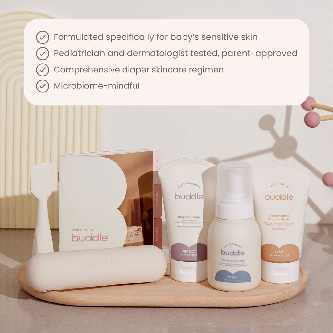 Buddle baby skincare products on a wooden tray with product details text overlay.