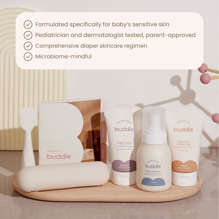 Buddle baby skincare products on a wooden tray with product details text overlay.