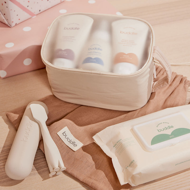 Buddle baby care products including bottles, wipes, and a container on a wooden surface.