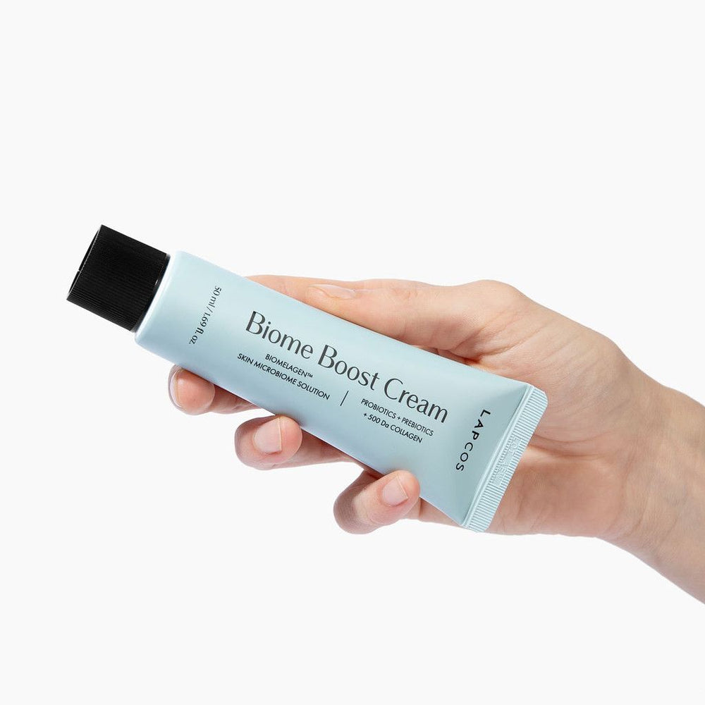 K-beauty Hand holding a tube of Biome Boost Cream against a white background