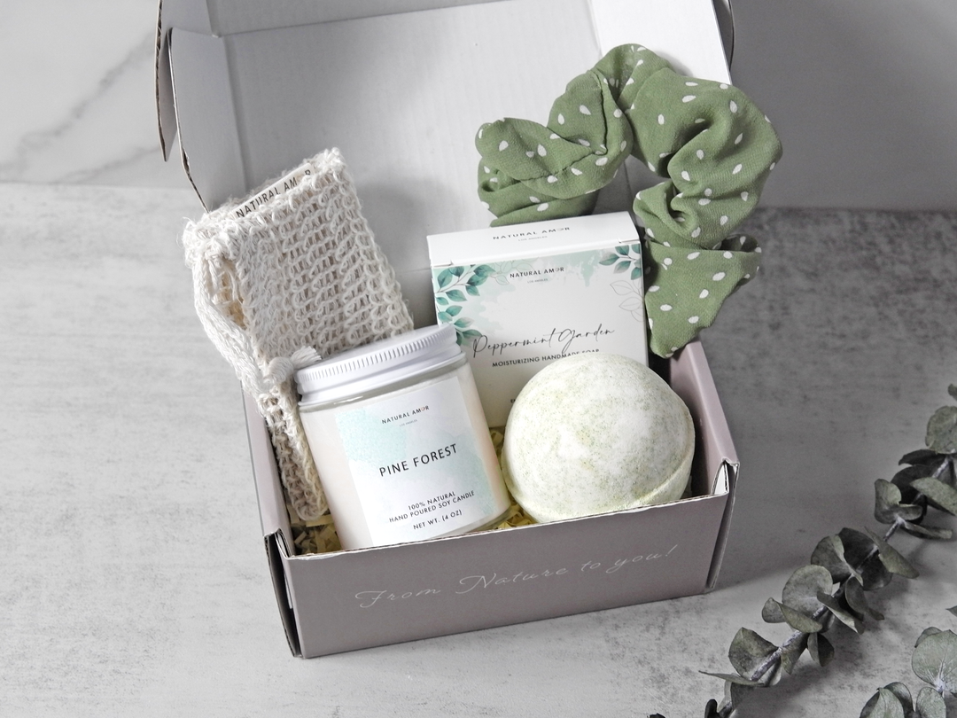 Gift set with bath bomb, candle, and towel in a box on a neutral background