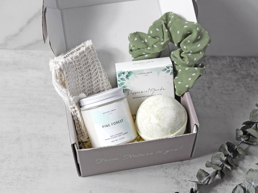 Gift set with bath bomb, candle, and towel in a box on a neutral background