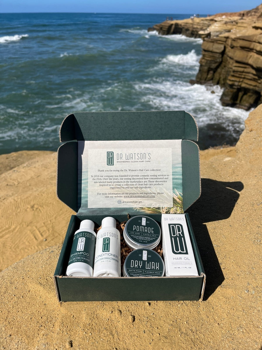 Open box of Dr. Watson's products for hair on a sandy beach with ocean view